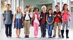 School Kids Eight smiling schoolchildren with backpacks lined up next to each other in the hallway of a school builiding..