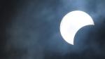 A partial solar eclipse looks like the Moon has taken a bite out of the Sun. Cloudy sky during a partial solar eclipse