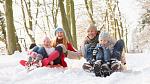 Smiling family sledging in the snow.