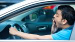 A man yawning and driving a car.