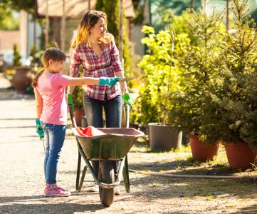 Mother and daughter with wheelbarrow in garden center.