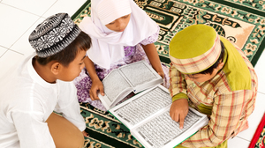 Three children reading the Koran on the floor.