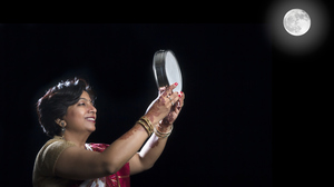 一个穿着传统印度服装的女人透过筛子看满月。