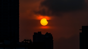 A partial eclipse of the Sun seen next to buildings.