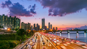  Traffic at sunset in Seoul, South Korea. Cars rushing along a highway in front of skyscrapers.