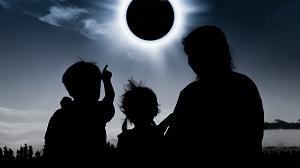 两个孩子和一个女人的剪影在日全食下观看钻石戒指的效果。