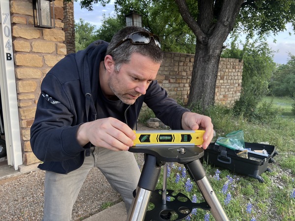 Man measuring telescope stand with a level tool.