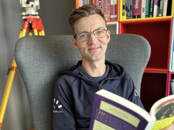 Man siting in chair in library, smiling at camera.