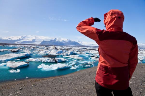 Female hiker looking across the Iceberg Lagoon, Jokulsarlon, Iceland filled with glacial Icebergs