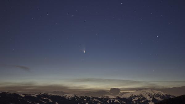 A comet glowing in the dark winter sky.