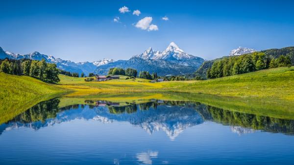 Bright blue sky and landscape reflecting in a lake in the Alps.