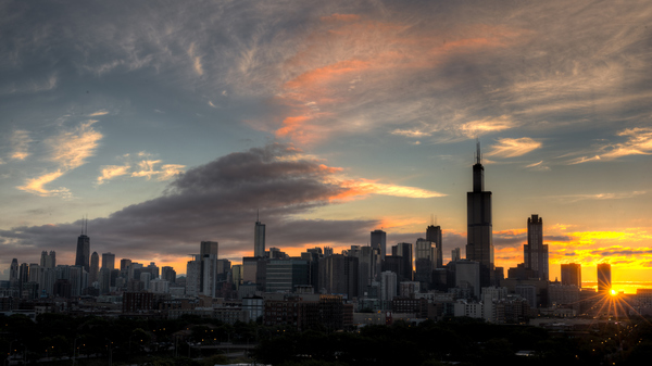 Skyline of Chicago with the rising Sun visible between the skyscrapers.