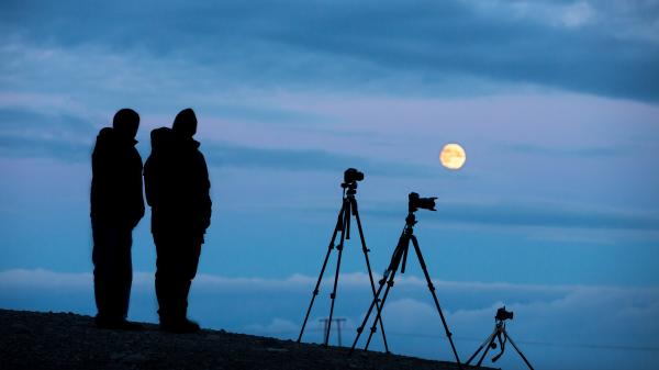 Silhouette of two photographers looking at the Full Moon.