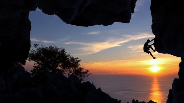 A man rock climbing at sunset.