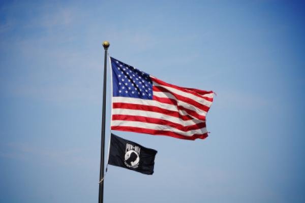 National League of Families’ POW/MIA flag is displayed with the United States flag.