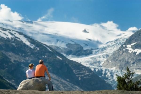 Couple taking a rest and day dreaming on a rock while watching an enormous glacial tongue.