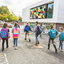En gruppe barn som går i sammen ved en moderne skole med fargerike skolesekker.