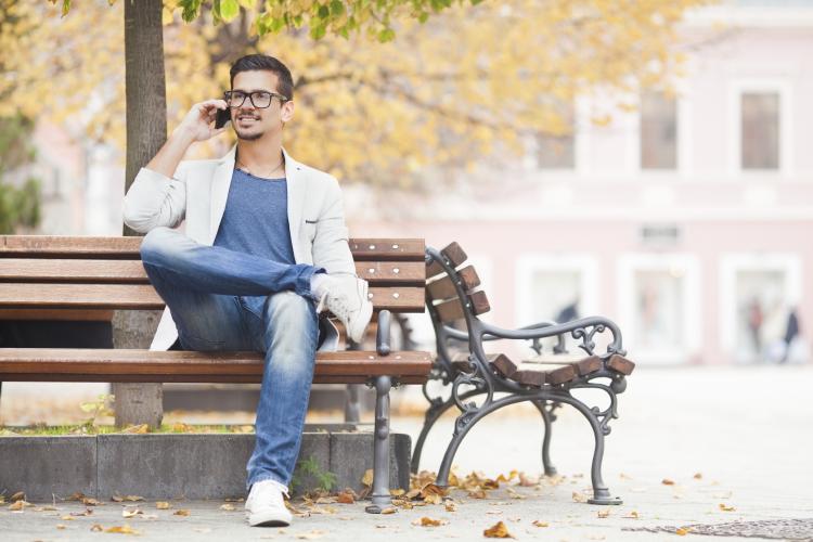 Relaxed man on park bench on the phone.
