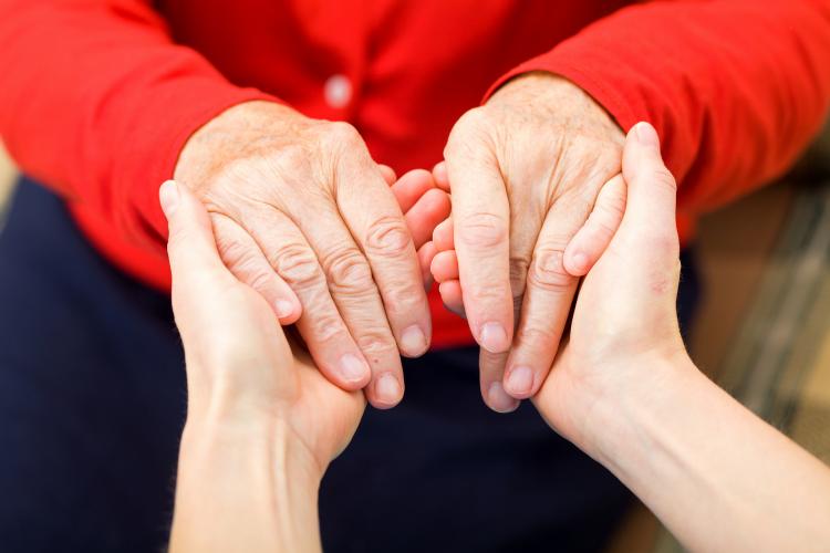 Young woman holding hands with elderly woman.