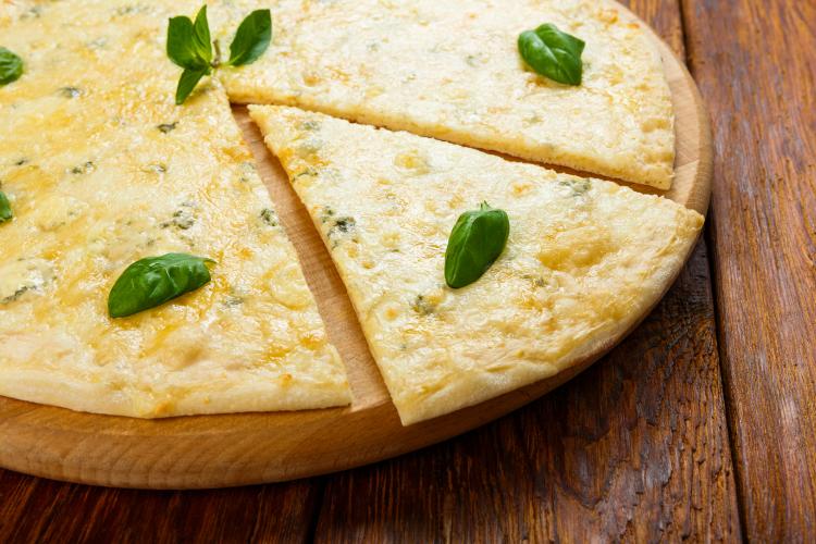 Four cheese pizza with basil leaves.