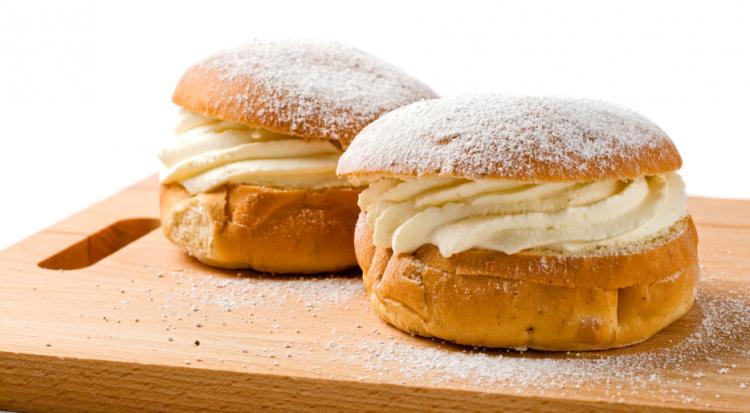 A traditional Norwegian Carnival Sunday treat: Two wheat buns filled with whipped cream topped with icing sugar on a plate. 