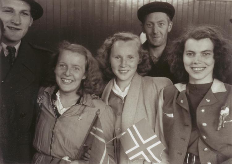 Fem smilende ungdommer med norske flagg 8. mai 1945.