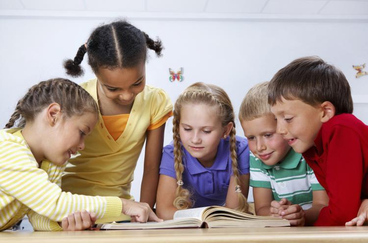 Small group of children reading a book together.