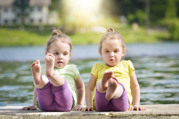 Twin girls exercising on a lake shore.