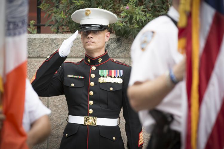 Marine in dress uniform saluting the American flag.