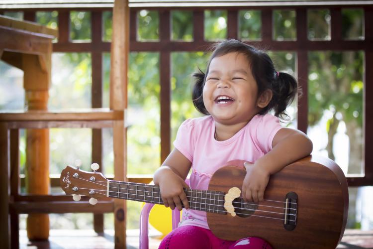 Cute little girl playing ukulele.