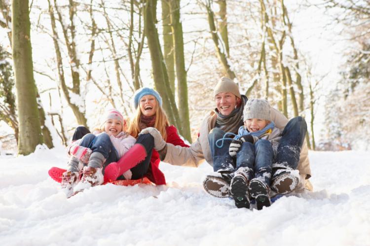 Smiling family sledging in the snow.