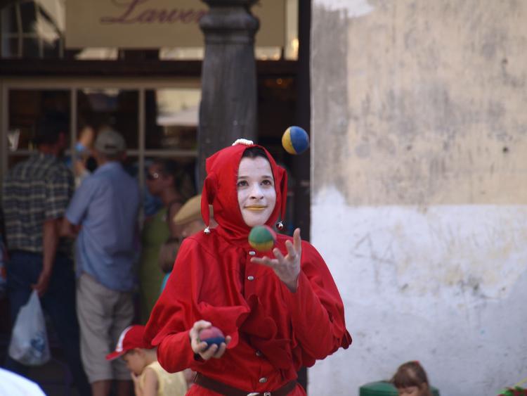 Young woman in clown costume juggling balls in an old market place on July 27, 2008, in Kazmierz Dolny, Poland.