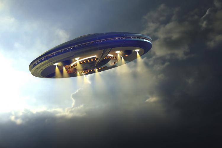 Artist rendition of alien UFO saucer flying above Earth with a background of clouds.