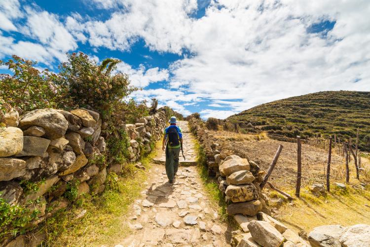 Female backpacker walking on ancient Peruvian trail.
