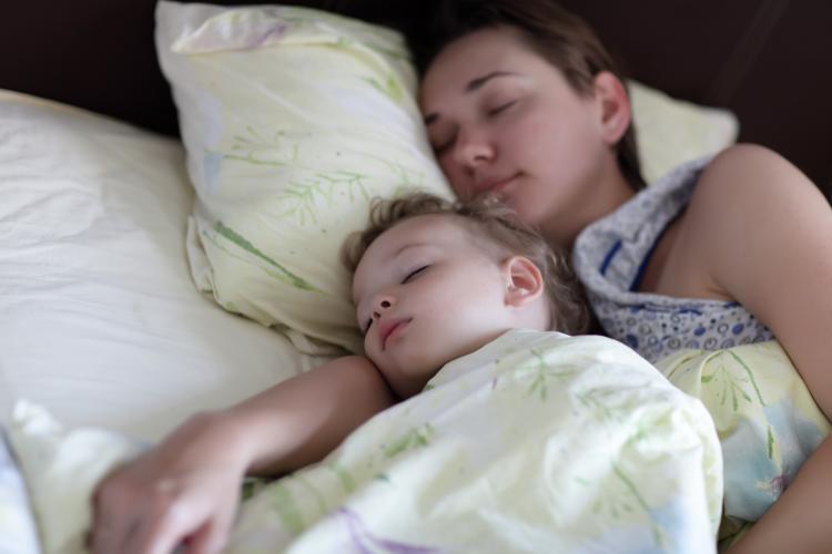 Mother with child are sleeping on a bed in the morning.