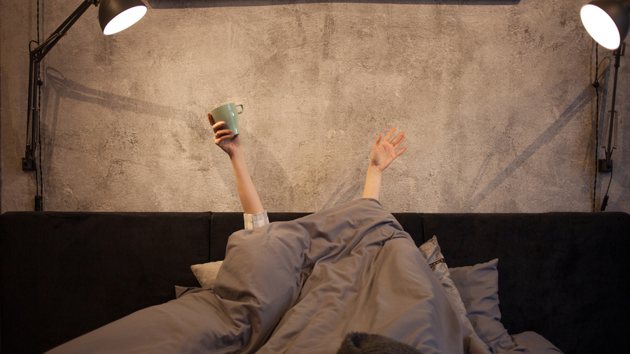 Tired person in bed with light on.