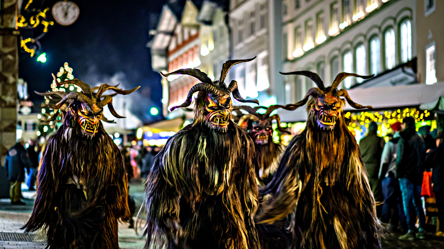 Three people in Krampus costumes at night in Bad Toelz, Germany.