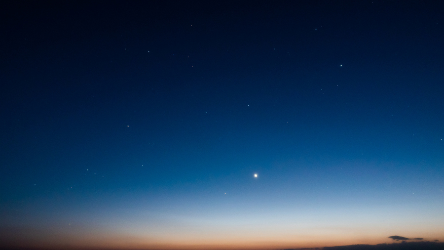 Venus shining brightly as the evening star over a dusky horizon.
