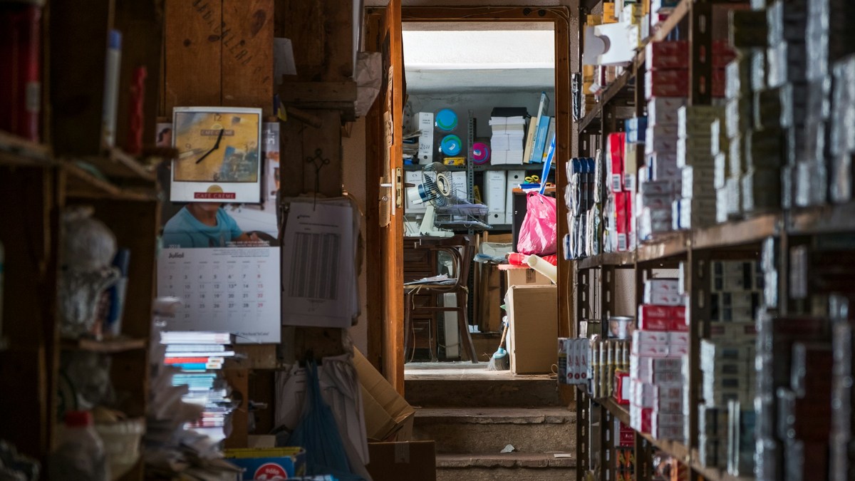 Cluttered storage room with shelves of supplies and a calendar on the wall.