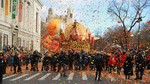 A large turkey float in the Macy's Thanksgiving Day Parade, surrounded by confetti and a crowd of spectators on a city street in New York.