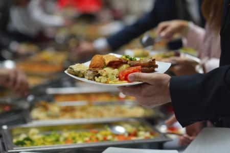People in a buffet line with full plates.