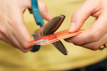 Woman cutting a credit card with scissors.