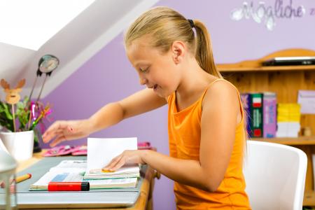 Girl sitting at home at her desk writing in a poetry album.