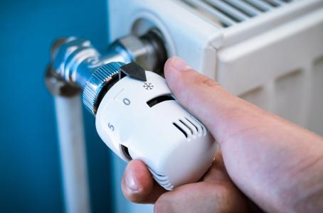 Hand turning down the dial on a radiator.