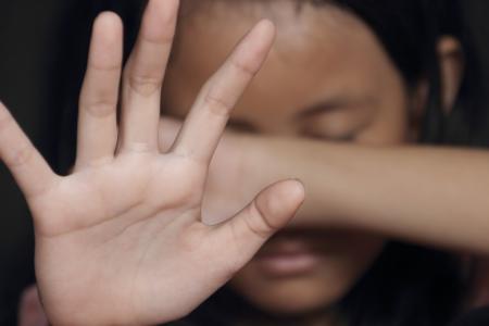 Young girl protecting her face and putting her hand out to say stop.