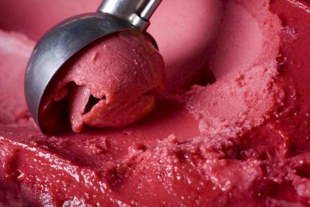 Red ice cream being scooped out.
