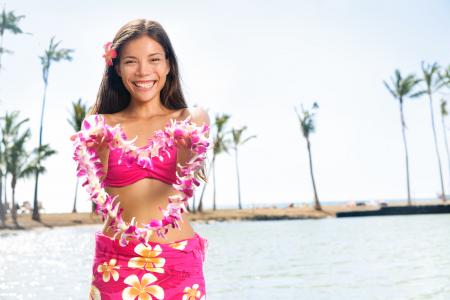 A young woman in aloha wear holding up a Hawaiian pink lei.