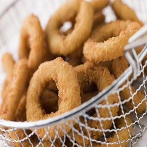 Breaded onion rings in a basket.