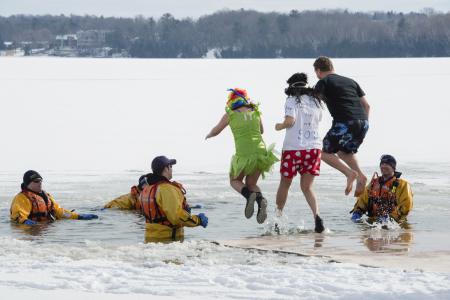 A group of people jump into Kempenfelt Bay during the annual Winterfest's Polar Bear Dip in Barrie, Canada.