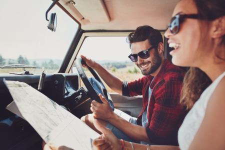 Couple in a car navigating with a road map.